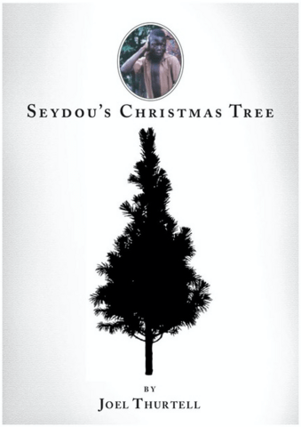 Book cover for "Seydou's Christmas Tree" by Joel Thurtell, featuring a silhouette of a Christmas tree and a circular image of Seydou above it.